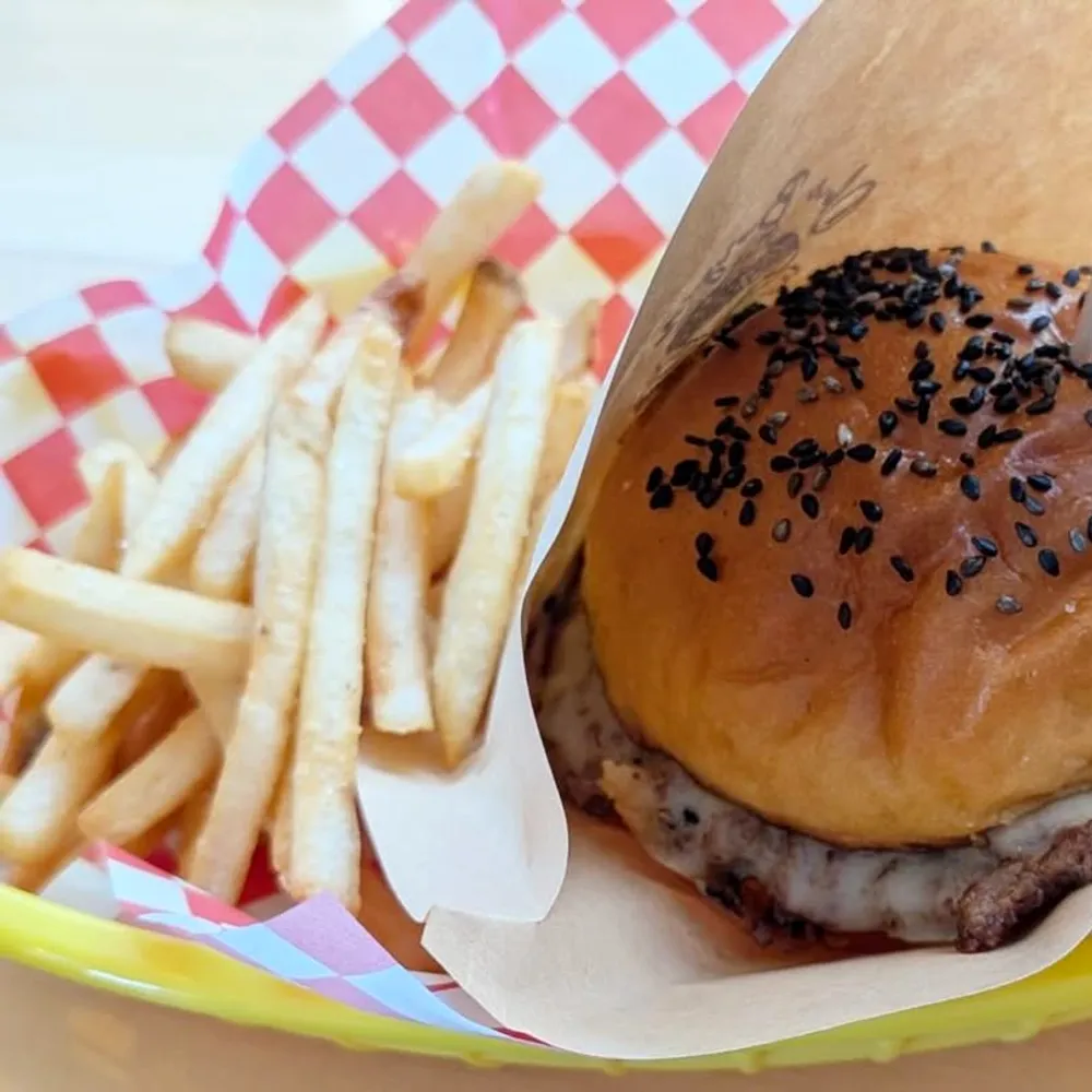 黒ごまを散らした自家製バンズのバーガーと山盛りのポテト、店名フラッグ
